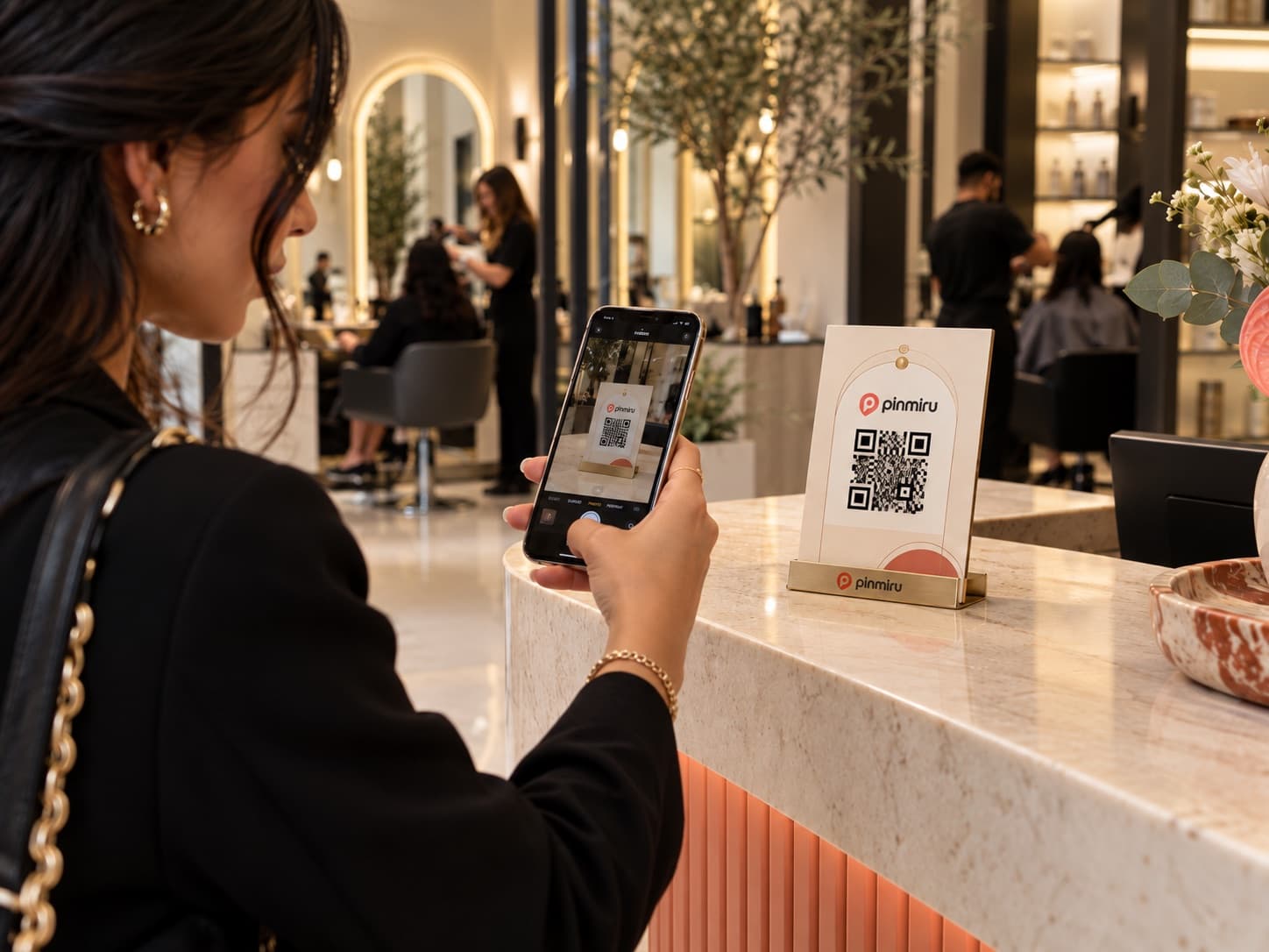 Une cliente scanne la carte QR PinMiru posée sur le comptoir du salon.